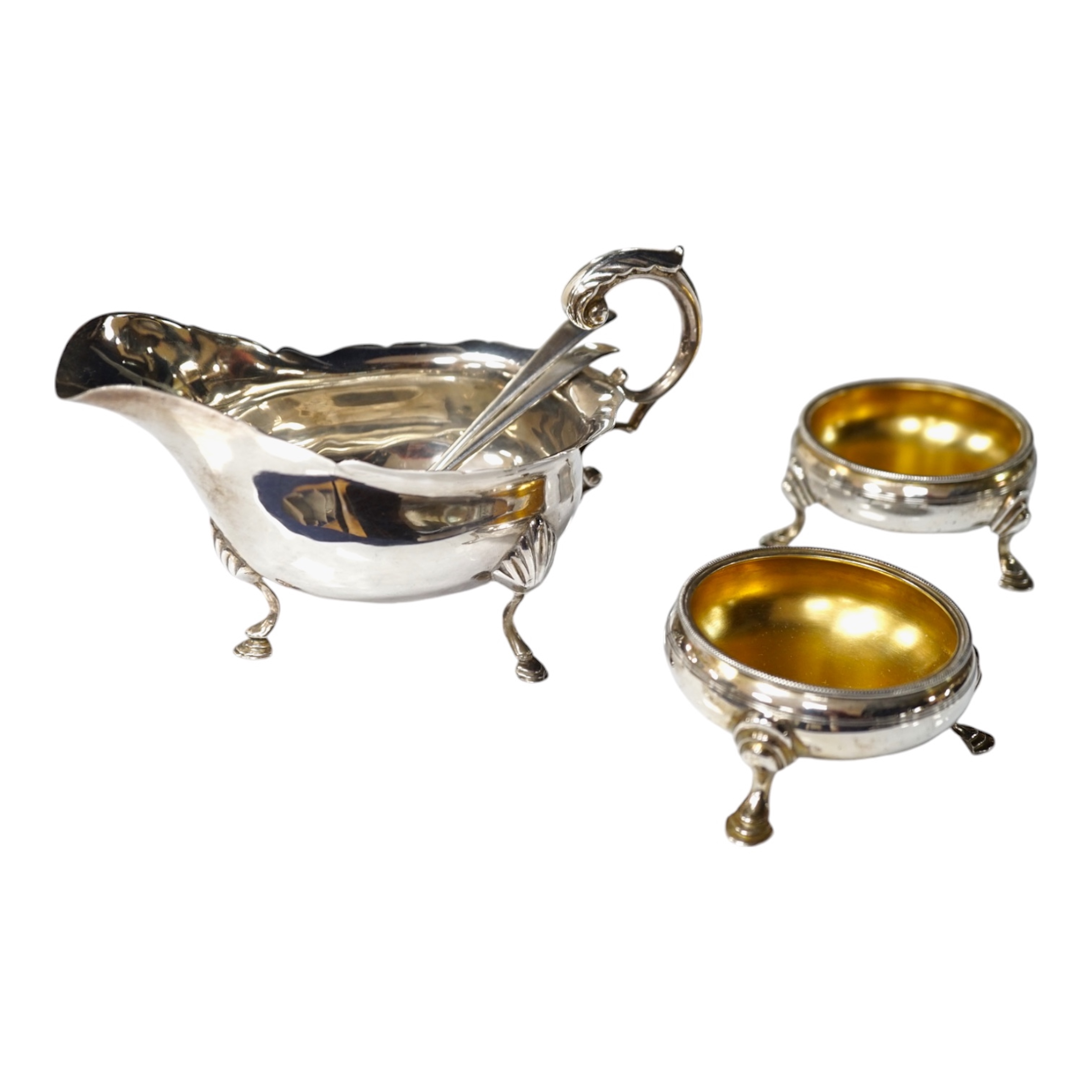 A pair of George III silver cauldron salts, London, 1765, with a pair of later Georgian mustard ladles, together with a late Victorian silver sauceboat. Condition - fair to good